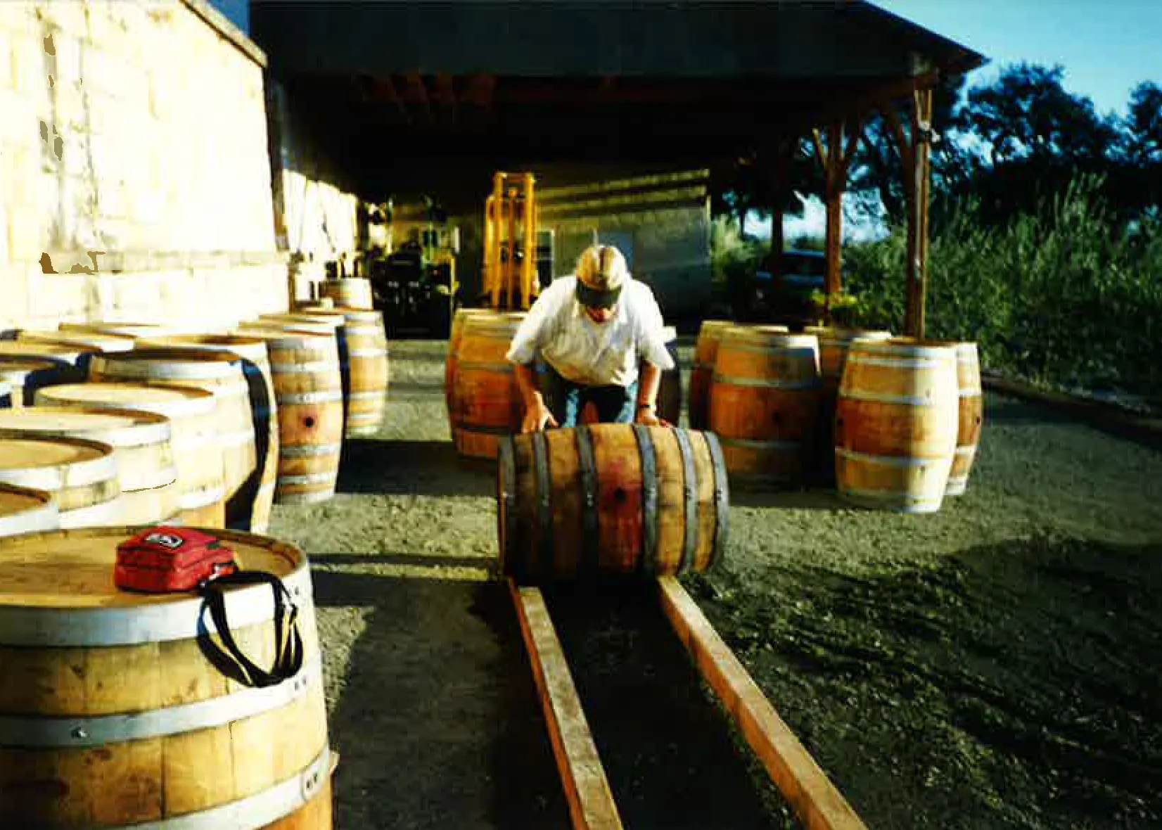 Person rolling wine barrels along a track