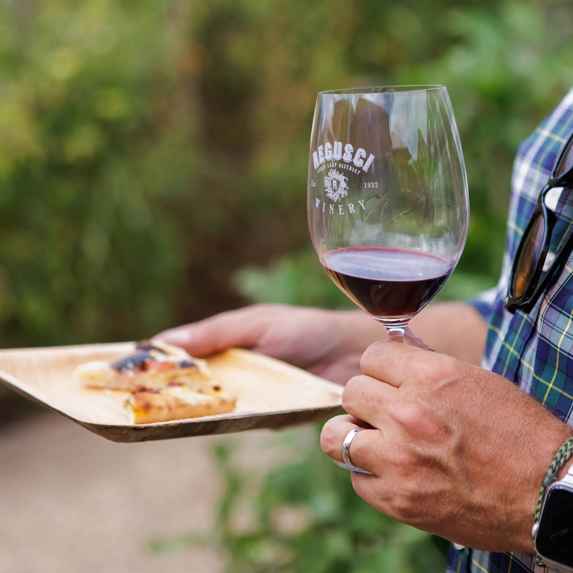 Person holding wine glass and plate of food